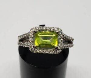 Silver ring with green gemstone and diamonds.