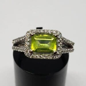 Silver ring with green gemstone and diamonds.