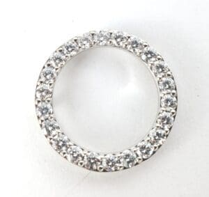 Diamond-studded circular silver jewelry piece.