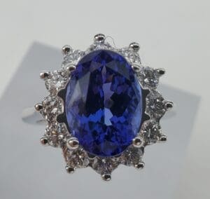 Oval blue gemstone ring with diamond halo.