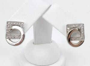 Silver and diamond geometric earrings on display.