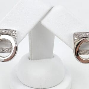 Silver and diamond geometric earrings on display.