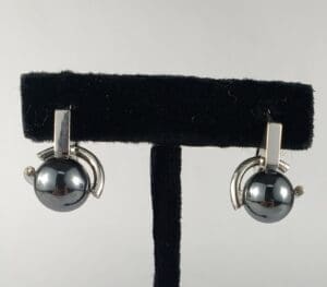 Silver earrings with spherical black stones.