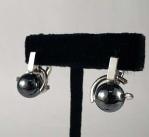Silver and black earrings on display stand.