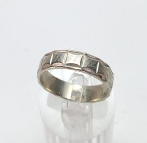 Geometric patterned silver ring on display stand.