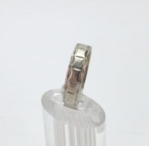 Silver ring with geometric pattern on stand.