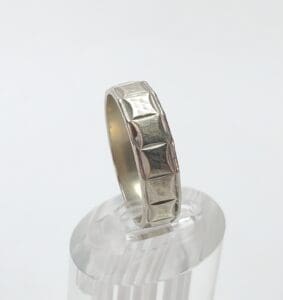 Silver ring with geometric pattern on display.