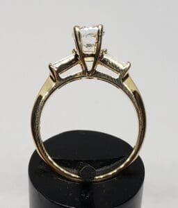 Gold ring with three diamond settings displayed.