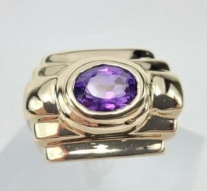 Gold ring with purple gemstone centerpiece.