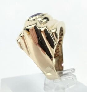 Gold ring with purple gemstone, side view.