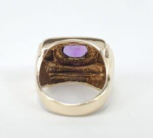 Gold ring with purple gemstone inside.