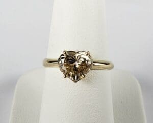 Heart-shaped diamond ring on display stand.