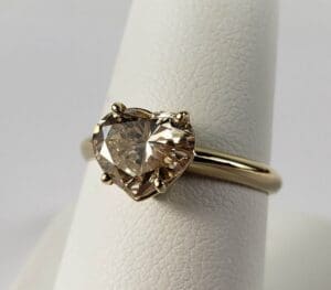 Heart-shaped diamond ring on display stand.