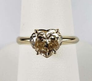 Heart-shaped diamond ring on display stand.
