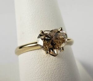 Heart-shaped diamond ring on display stand.