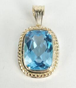 Gold pendant with large blue gemstone.