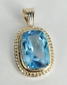 Blue gemstone pendant with gold setting.