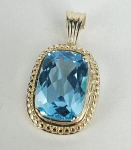 Blue gemstone pendant with ornate silver setting.