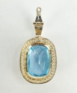 Gold pendant with large blue gemstone.