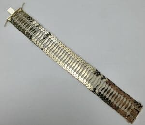 Wide gold bracelet with intricate design.