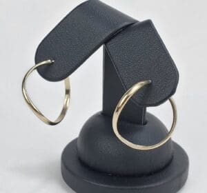 Gold hoop earrings on black display stand.