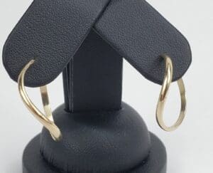 Gold hoop earrings on black stand.