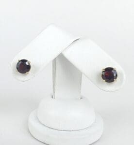 Gold stud earrings with dark gemstones.