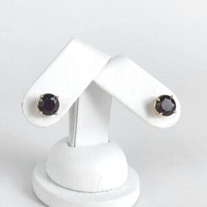 Gold stud earrings with dark gemstones.