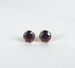 Gold earrings with round red gemstones.