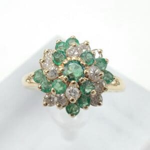 Gold ring with emerald and diamond cluster.