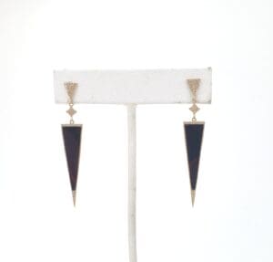 Long triangular black and gold earrings displayed.