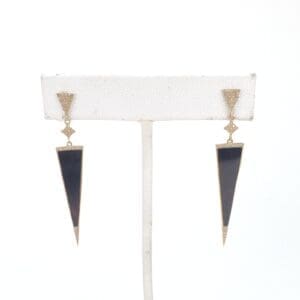 Black triangular earrings on white display stand.