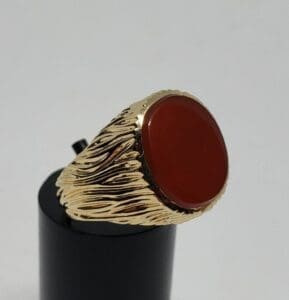 Gold ring with red circular stone.
