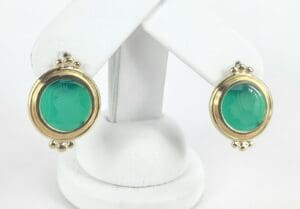 Gold-framed green cameo earrings on display.