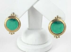 Gold earrings with green gemstones displayed.