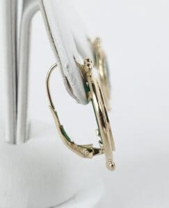 Gold earrings on white display stand.