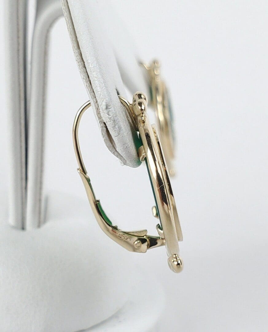 Gold earrings on white display stand.
