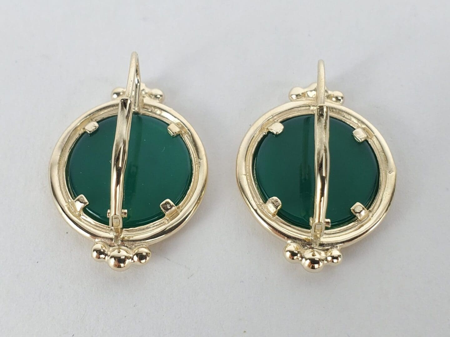 Gold earrings with green circular stones.
