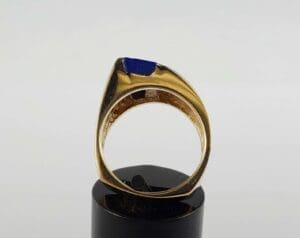 Gold ring with blue stone on stand.