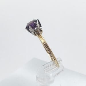 Gold ring with purple gemstone on stand.