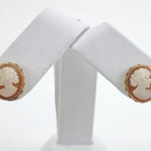 Cameo earrings on white display stand.