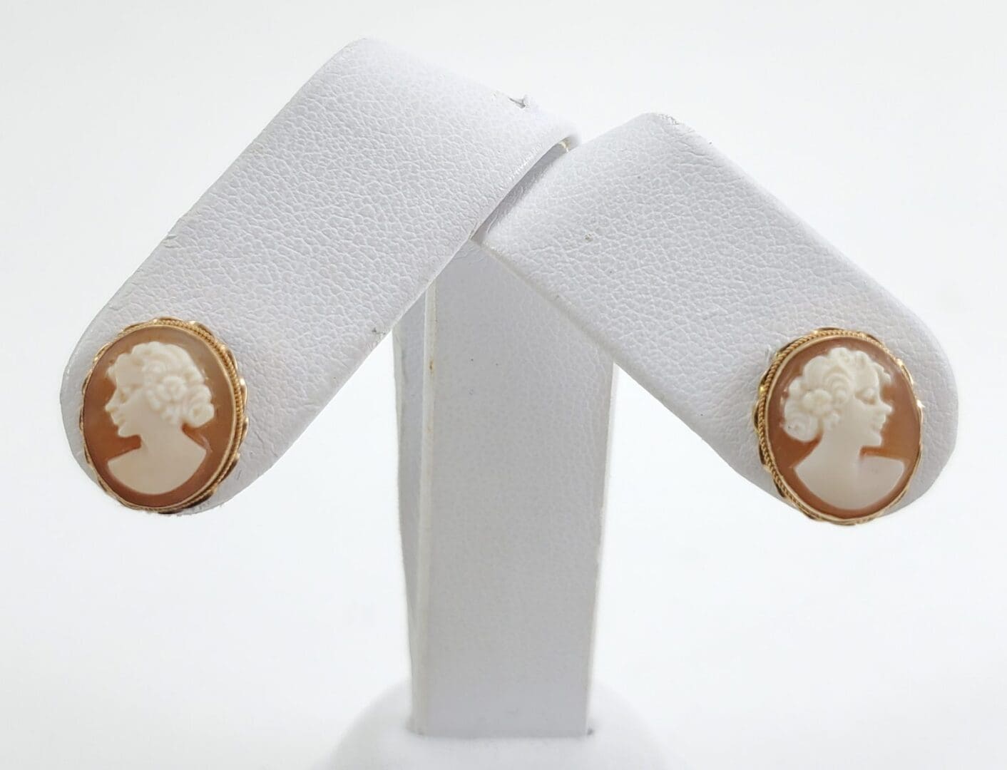 Cameo earrings on white display stand.