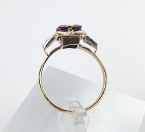 Gold ring with purple gemstone on display.