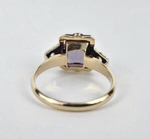 Gold ring with purple gemstone, side view.