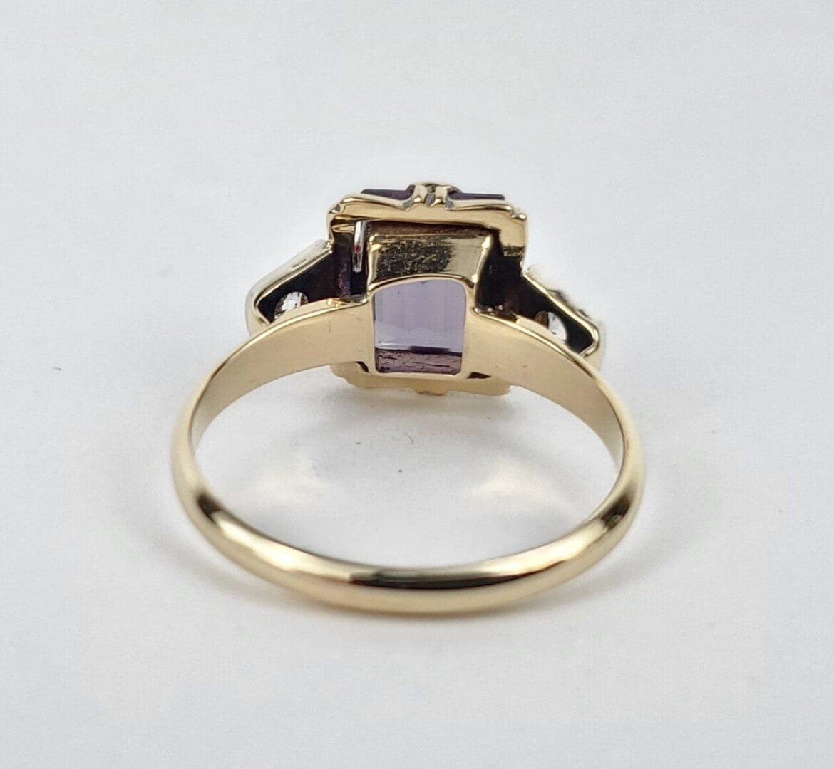 Gold ring with purple gemstone, side view.