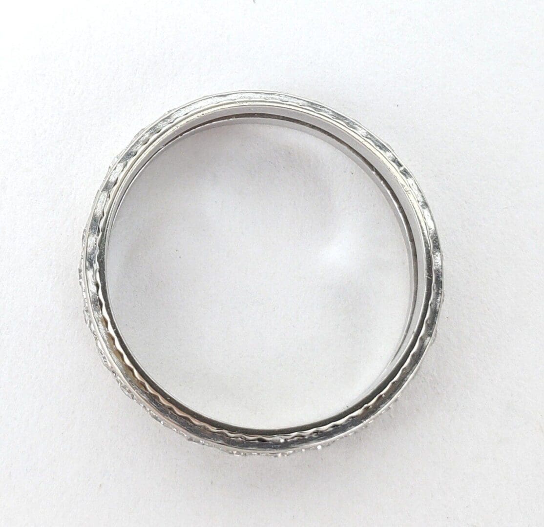 Silver ring with textured design on white background.