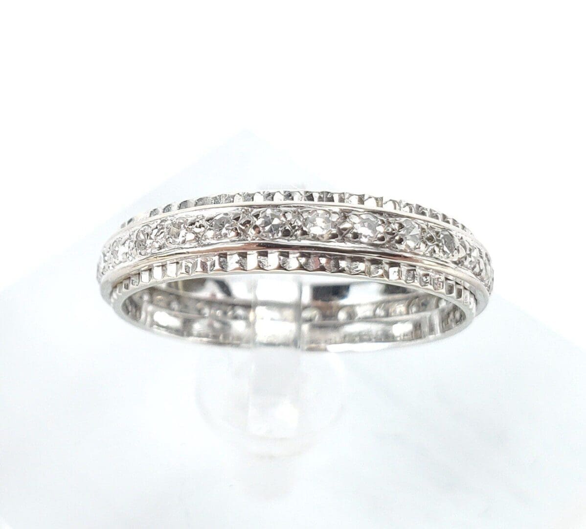 Silver diamond-studded ring on display stand.