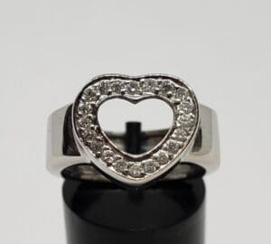 Heart-shaped diamond ring on display stand.