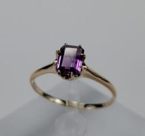 Gold ring with purple gemstone on display.