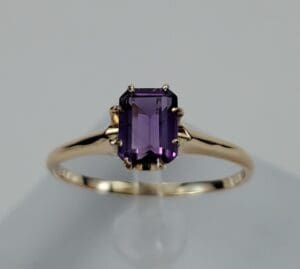 Gold ring with purple gemstone centerpiece.